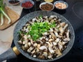 Sliced mushrooms and green onions are cooked in a pan. Spices and green onions are visible in the background. Royalty Free Stock Photo