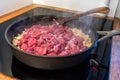 sliced onions and meat are frying in a pan