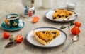 Sliced open pie with pumpkin and prunes on a ceramic plate on a gray concrete background. Pumpkin recipes. Thanksgiving desserts