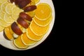 Sliced orange, apple and lemon slices on a white fruit plate on a black background Royalty Free Stock Photo