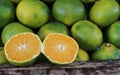 Sliced orange on a pile of green oranges in a wooden box at the market Royalty Free Stock Photo