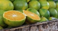 Sliced orange on a pile of green oranges in a wooden box at the market Royalty Free Stock Photo