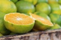 Sliced orange on a pile of green oranges in a wooden box at the market Royalty Free Stock Photo