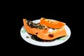 Sliced ??papaya fruit on a plate on a black background. Royalty Free Stock Photo