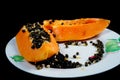 Sliced ??papaya fruit on a plate on a black background. Royalty Free Stock Photo