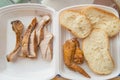 Sliced pieces of cold baked pork in a plastic container, with slices of wheat bread and fried chicken wing, an Royalty Free Stock Photo