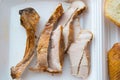 Sliced pieces of cold baked pork in a plastic container, with slices of wheat bread and fried chicken wing, an Royalty Free Stock Photo