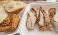 Sliced pieces of cold baked pork in a plastic container, with slices of wheat bread and fried chicken wing, an Royalty Free Stock Photo