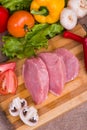 Sliced pieces of raw meat for barbecue with fresh Vegetables tomatoes, lettuce on wooden surface. Top view. Royalty Free Stock Photo