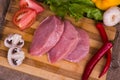 Sliced pieces of raw meat for barbecue with fresh Vegetables tomatoes, lettuce on wooden surface. Top view. Royalty Free Stock Photo