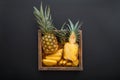 Sliced Pineapple. Bromelain whole pineapple tropical summer fruit halves pineapple black dark background in wooden box