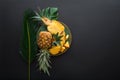 Sliced Pineapple on plate with tropical palm leaves. Bromelain whole pineapple summer fruit halves pineapple on black Royalty Free Stock Photo