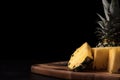 Sliced pineapple stands on a wooden board on a dark background