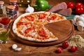 Sliced pizza. Pizza margarita with tomato sauce, fresh mozzarella, parmesan and basil on the wooden rusty background Royalty Free Stock Photo