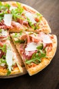 Sliced pizza with prosciutto parma ham, arugula (salad rocket) and parmesan on dark wooden background close up Royalty Free Stock Photo