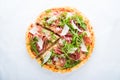 Sliced pizza with prosciutto parma ham, arugula (salad rocket) and parmesan on white background top view