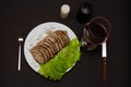 Glass of red wine and fork sliced pork meat with lettuce leaves on a plate Royalty Free Stock Photo