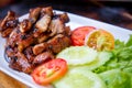 Sliced pork roasted thai style with green leaves salad on rustic plate with cutlery