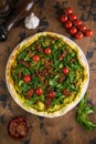 A sliced portion of spinach and tomatoes pies quiche with autumn leaves on white marble table