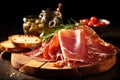 Sliced prosciutto with bread and olives on wooden board