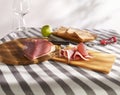 sliced prosciutto on a wooden board. pork ham on a light background. composition meat delicacy and bread.