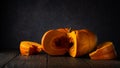 sliced pumpkin lies on a wooden table against the background of a dark gray wall with a spot of light. artistic moody still life