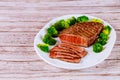 Sliced rare beef tenderloin with broccoli on white plate