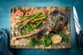 Sliced rare grilled or barbecued tomahawk beef steak on a griddle with fresh rosemary and tomato in a close up view. Royalty Free Stock Photo