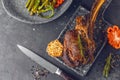 Sliced rare grilled or barbecued tomahawk beef steak on a griddle with fresh rosemary and tomato in a close up view. Royalty Free Stock Photo