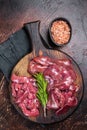 Sliced Raw chicken liver, fresh fowl offals on wooden board. Dark background. Top view