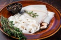 Sliced raw rings Calamari in a rustic plate with rosemary. Dark background. Top view Royalty Free Stock Photo