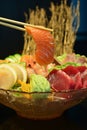 Sliced raw salmon with chopsticks holding it