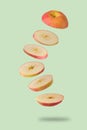 Sliced red apple flying on light green background. Levitation of fruit floating in the air. Creative minimal concept