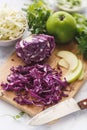 Sliced Red Cabbage, White Cabbage, Green Apple and Herbs on Kitchen Table Royalty Free Stock Photo