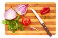 Sliced red onion, tomatoe, pepper, garlic, basil and parsley with knife on wooden board over white background. Royalty Free Stock Photo