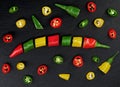 Sliced red, yellow and green chillies form a mixed colorful chili pepper on a black slate background, top view Royalty Free Stock Photo