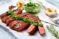 Sliced rib eye beef steak with chimichurri sauce and spices on white paper. Striploin cooked on the grill Royalty Free Stock Photo