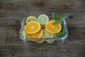 Sliced rings of orange, lemon, lime and sprig of mint in a glass plate on a wooden rustic background. Healthy food. Royalty Free Stock Photo