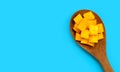 Sliced ripe mango cubes on wooden spoon on blue background Royalty Free Stock Photo