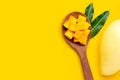 Sliced ripe mango cubes on wooden spoon on yellow background Royalty Free Stock Photo