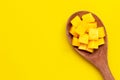 Sliced ripe mango cubes on wooden spoon on yellow background Royalty Free Stock Photo