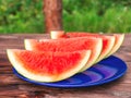 Sliced ripe red watermelon on a blue plate on a wooden table Royalty Free Stock Photo