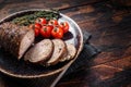 Sliced roast pork roulade - Porchetta on a plate with spices. Wooden background. Top view. Copy space Royalty Free Stock Photo