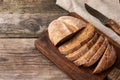 Sliced round baked rye flour bread on a wooden cutting board