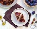 Sliced round honey cake or muffin with fresh plums on a light grater on a light concrete background. Plum baked goods Royalty Free Stock Photo