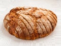 Sliced round loaf of rye bread with an appetizing crispy brown crust on a gray linen tablecloth. Tasty, usefull and nutritious.