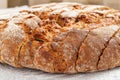 Sliced round loaf of rye bread with an appetizing crispy brown crust on a gray linen tablecloth. Tasty, usefull and nutritious. Royalty Free Stock Photo