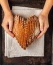 Sliced round loaf of rye bread in the shape of a heart on a linen napkin in children`s hands