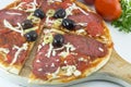 Sliced round pizza and raw vegetables on a wooden plate Royalty Free Stock Photo