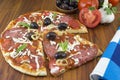 Sliced round pizza and raw vegetables on a wooden table Royalty Free Stock Photo